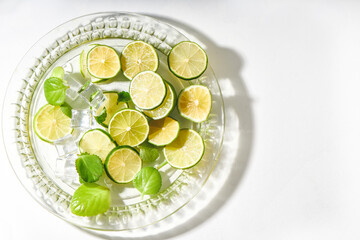 lime and ice served in plate on white background with hard shadows