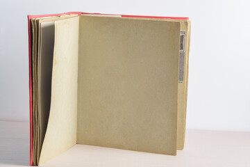 An old faded open photo album or photo book with a red cover, with yellowed pages on a light background. Copy space, minimal style, the concept of storing memories.