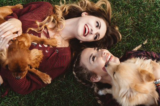 Two female friends in their twenties playing with their dogs outside in autumn