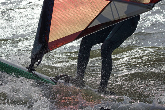 Silhouetted windsurfers in windy and high-contrast conditions on the IJsselmeer lake.