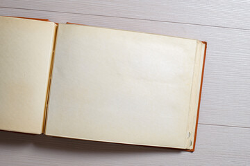 An old faded open photo album or photo book with a red cover, with yellowed pages on a light...