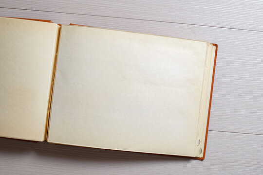 An old faded open photo album or photo book with a red cover, with yellowed pages on a light background. Copy space, minimal style, the concept of storing memories.