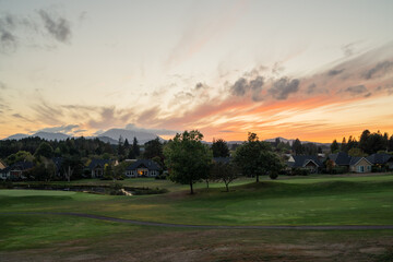 An Oregon sunset at a green golf course with mountains in the distance