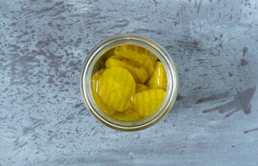 Hamburger dill pickles in a jar on a gray table