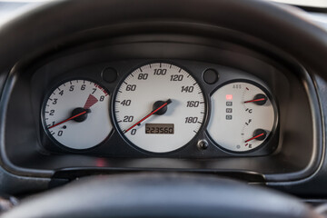 Car dashboard with white dials and red arrows on the speedometer, tachometer and other vehicle...