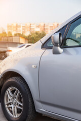 Front wing section of a silver car with wheel and side mirror of a Japanese station wagon after being repaired and rebuilt from an accident.