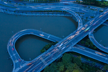 top down drone shot of motorway and interchange above a river with curves and streaks from...