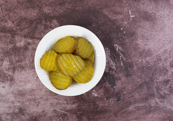 Hamburger dill pickles on a maroon table