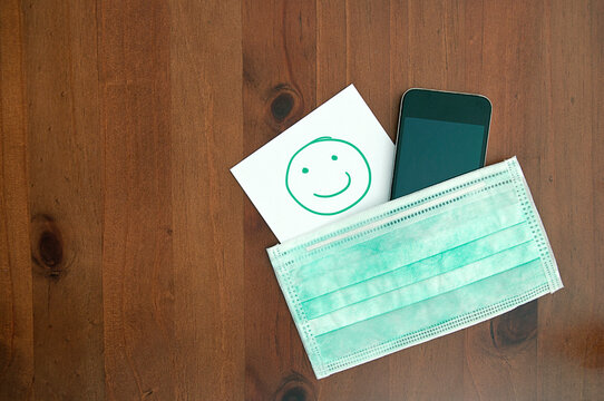 healthcare_hygienic mask_smartphone_smile_paper_wooden background