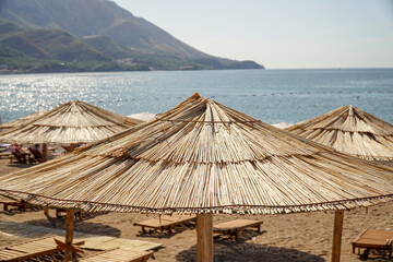   Reed beach umbrella on the background of the sea and mountains. The concept of summer holidays and tourism.