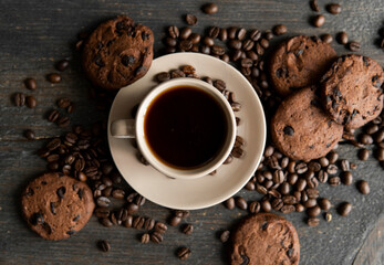 Coffee cup with cookies on wooden table background. Mug of black coffee with scattered coffee beans and cookies on a wooden table. Fresh coffee beans.