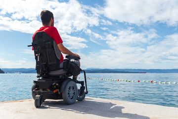 Man sitting in a wheelchair on the beach. Dangers of jumping into water from heights. Head and...