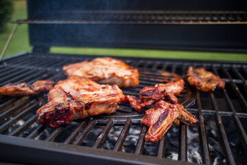 Home barbecue with charcoal in the backyard grilling steaks and other meats for carnivore diet.