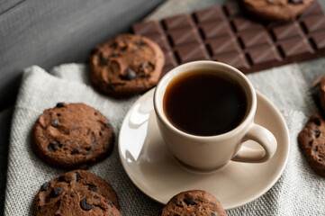 Coffee cup with cookies and chocolate on wooden table background. Mug of black coffee with chocolate cookies. Fresh coffee beans.