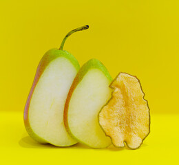 dehydrated dried pears slices and fresh ripe pear on a yellow background, healthy snack for children and adults