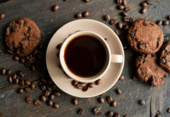 Coffee cup with cookies on wooden table background. Mug of black coffee with chocolate cookies. Fresh coffee beans.