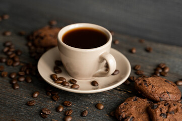 Coffee cup with cookies on wooden table background. Mug of black coffee with chocolate cookies. Fresh coffee beans.