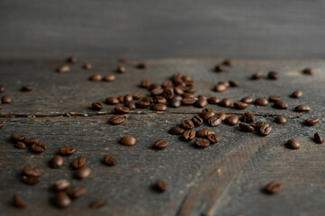 Roasted arabica coffee beans scattered on a wooden table. Fresh coffee beans.