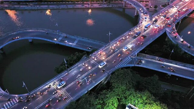 top down panning drone shot of Nguyen Van Cu bridge, motorway and interchange above the Kenh Te canal with curves and streaks from headlights in Ho Chi Minh City, Vietnam