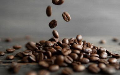 Roasted arabica coffee beans falling on a wooden table. Fresh coffee beans.