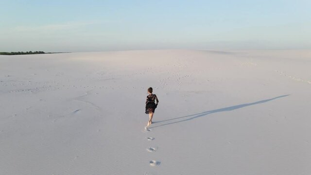 Woman in lace black dress runs in desert.