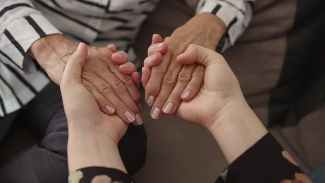 Close up mature elderly woman holding hands of grown up daughter, showing love and care. High quality 4k footage