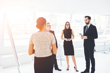 Fototapeta premium Male and female experts discussing successful strategy for developing productivity of company on business meeting standing in office interior. Young professionals solving serious financial problems