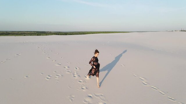 Woman in lace black dress runs in desert.