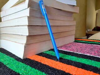 Pile of old books with writing pen near it on study table