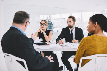 Back view of confident CEO explaining to employees concept of successful project coaching staff on meeting.Prosperous business partners concentrated on discussing collaboration during parleys