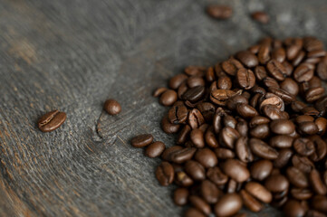 Roasted arabica coffee beans scattered on a wooden table. Fresh coffee beans.