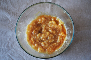 pounded banana and coconut oil in a glass bowl on the table in the kitchen.  making banana cake gluten-free and lactose-free