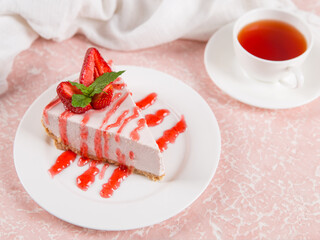 Sweet breakfast, tea and delicious cheesecake with fresh strawberries and mint, homemade recipe without baking, on a pink stone table. Copy space.