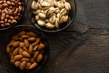 Almond, pistachio and peanut in a small plates which standing on a black table. Nuts is a healthy vegetarian protein and nutritious food.