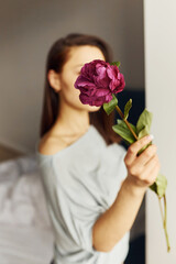 Holding flowers. Young woman resting and spending weekend at home alone at home