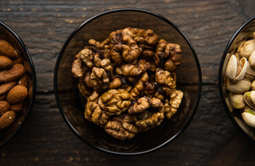 Almond, pistachio and walnut in a small plates which standing on a black table. Nuts is a healthy vegetarian protein and nutritious food.