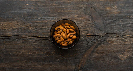 Almonds in a small plate on a vintage wooden table. Almond is a healthy vegetarian protein nutritious food. Natural nuts snacks.