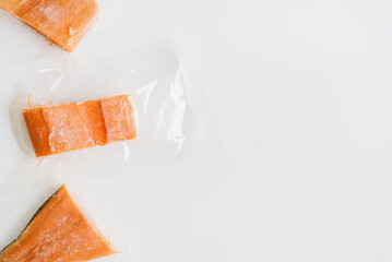 Frozen salmon fillets in plastic package on white background, top view. Seafood storage. Red fish