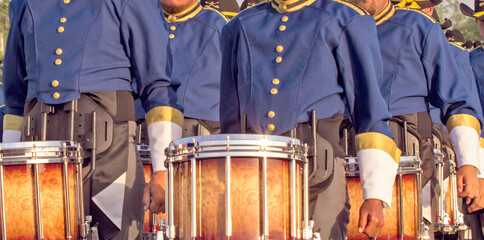 Marching band performing with musical instruments for a crowd. Drummers marching on a field.