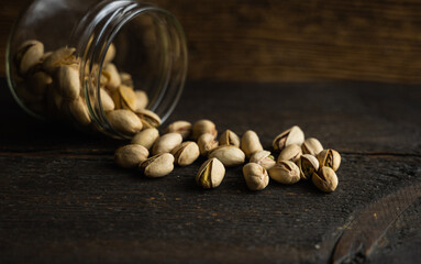 Pistachios scattered on the vintage table from a jar. Pistachio is a healthy vegetarian protein...