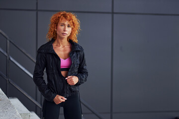 Fototapeta premium Young european redhead woman in sportive clothes standing outdoors