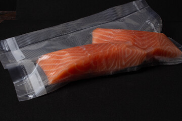 Piece of gourmet oceanic salmon vacuum packed in clear plastic ready for freezing lying on a wooden table. Top View