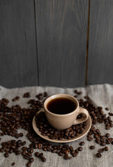 Coffee cup with roasted coffee beans on linen background. Mug of black coffe with scattered coffee beans. Fresh coffee beans.