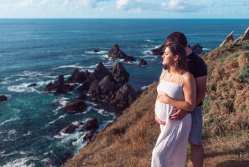Pregnant couple on top of a cliff near the ocean