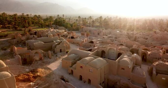 Aerial Traditional mud house resort desert Eco village with a glass glow and palm trees landscape in morning sunrise