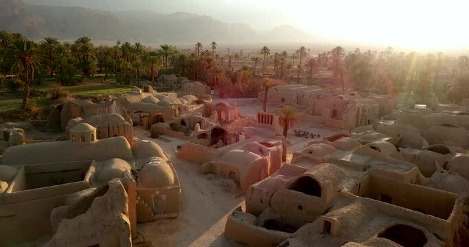 Aerial landscape, oasis desert Eco village and palm trees garden and saffron fields with mud house buildings ruin structure and mountain view in sunrise time early morning