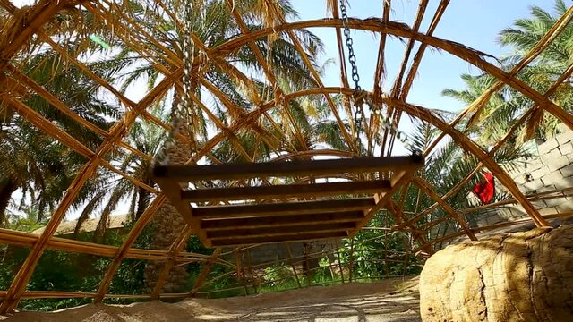 Traditional swing game with chains in a rural structure in a palm trees garden field in Rigan Kerman Iran