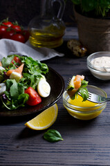 Salad in focus on dark ornate table, with vegetables and salmon, vertical image on dark background