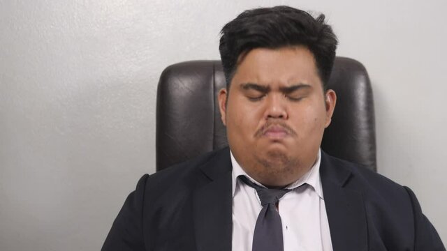 A funny Asian fat businessman wearing a suit look like the head of corporate executive or business manager was listening and predicting something for a while, but he declined very hard.