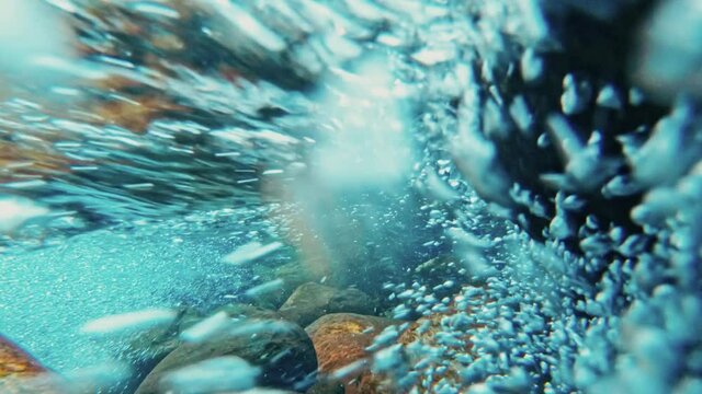 Mountain river with rocks, clear water and bubbles, underwater video shooting